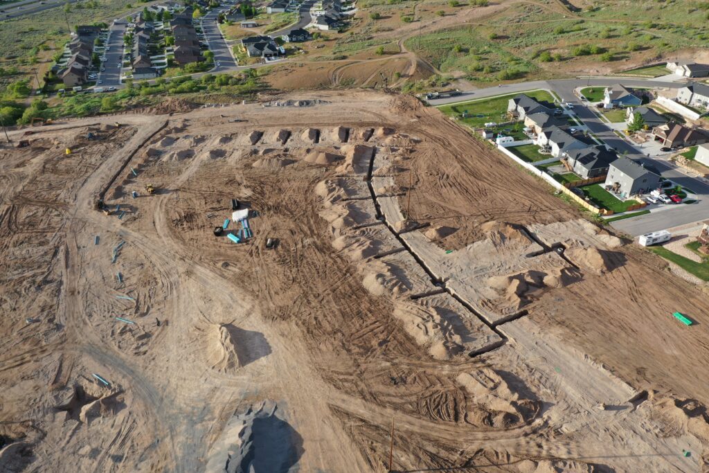 Aerial view of a construction site with earthwork near a residential area.